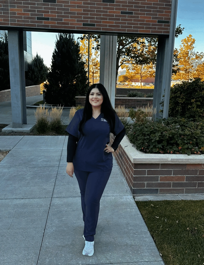 Person in scrubs standing outside a building.