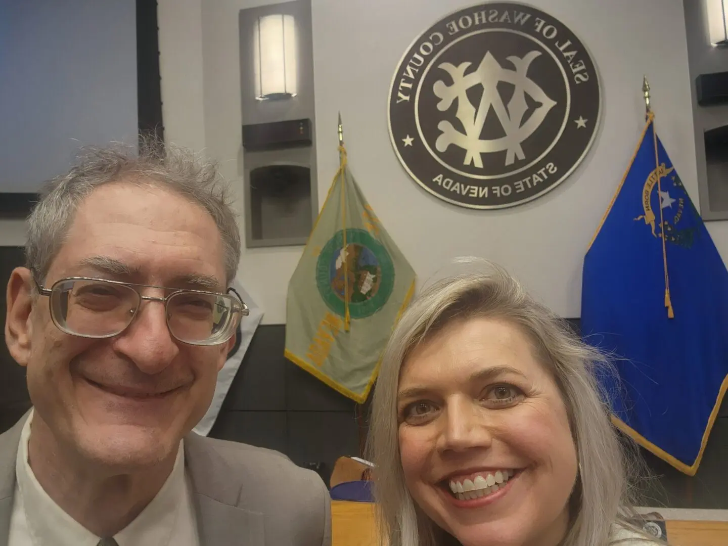 A man and woman posing for the camera in front of a sign.